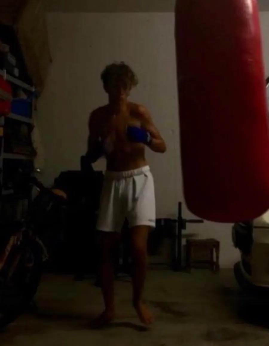 A teenage Gio boxing in a dim home garage next to a red heavy bag